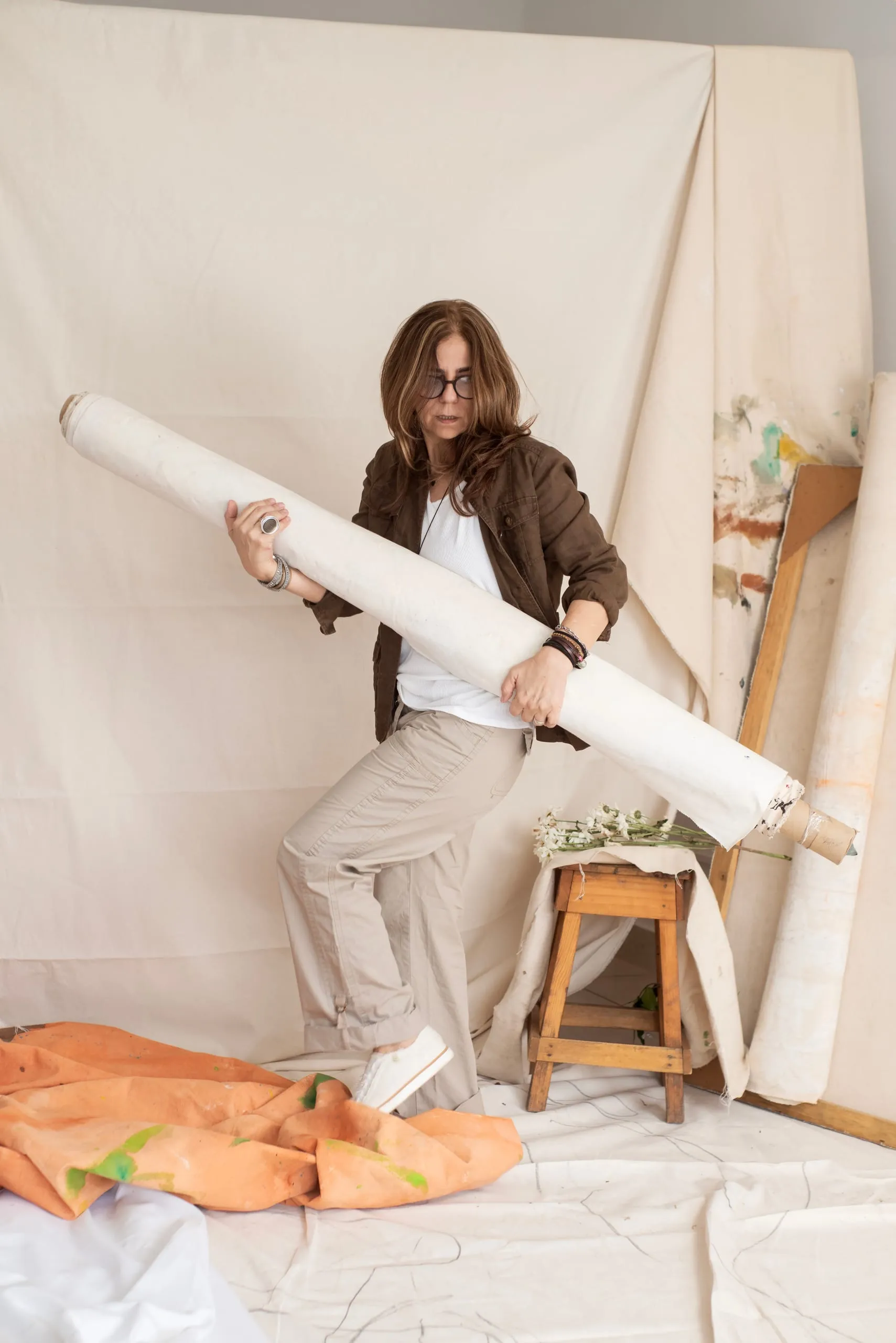 Elsa Basil carrying a rolled canvas across her studio